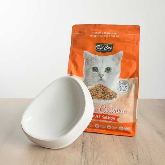 Kit Cat cat food package with a white bowl on a light wooden surface