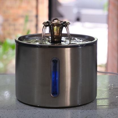 Stainless steel pet water fountain on a table with a blurred outdoor background
