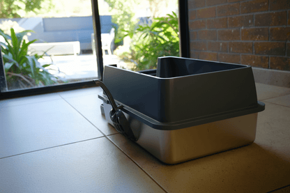 Enclosed cat litter box with flip-top lid, gray and beige body, closed front