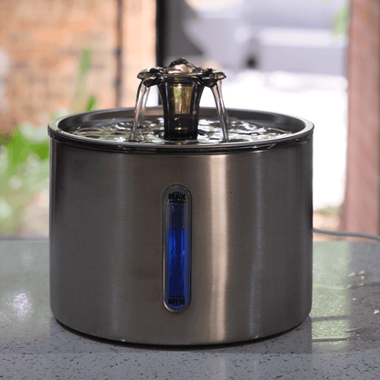 Stainless steel pet water fountain on a table with a blurred outdoor background