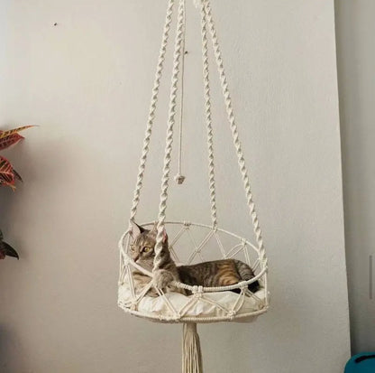 Handwoven macramé cat hammock with a cat inside and tassel trim