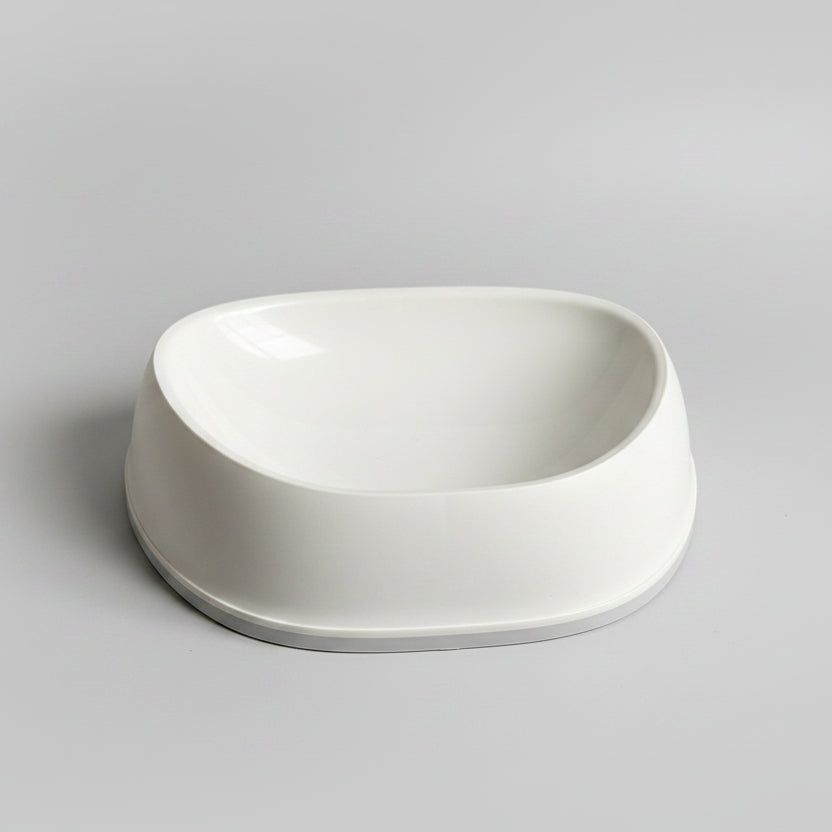 White SensiBowl pet bowl  on a white surface, with a bag of cereal in the background.